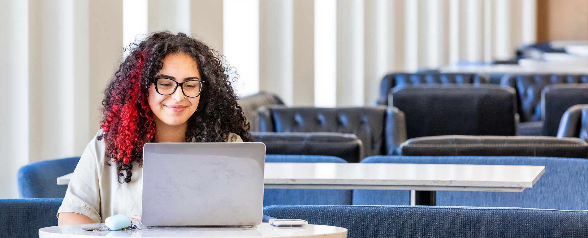 Woman smiling, working towards online degree with laptop.