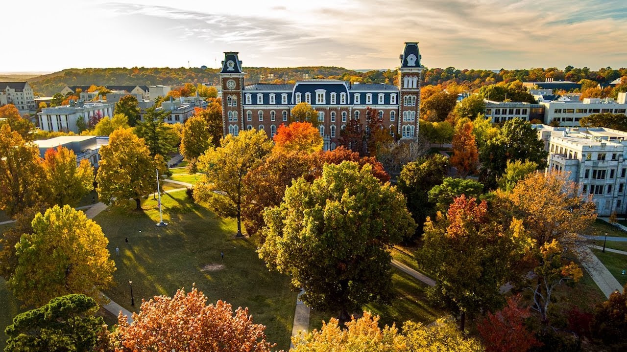 Aerial view of Old Main surrounded by colorful autumn trees and landscaped walkways.