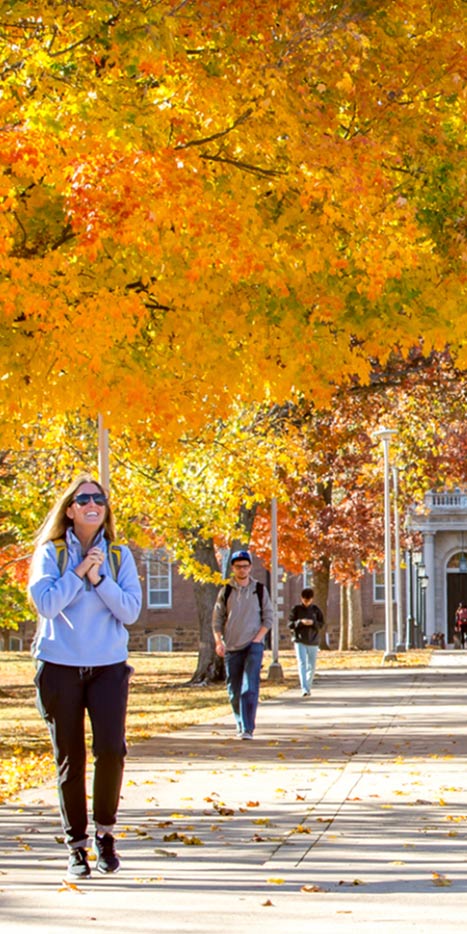 Fall campus scene with student walking