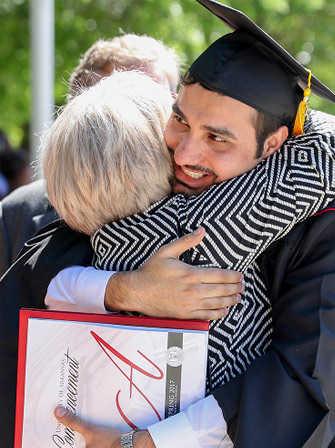 Bronze sculpture of three wild hogs on a rocky fountain with cascading water, set outdoors under a blue sky with clouds.